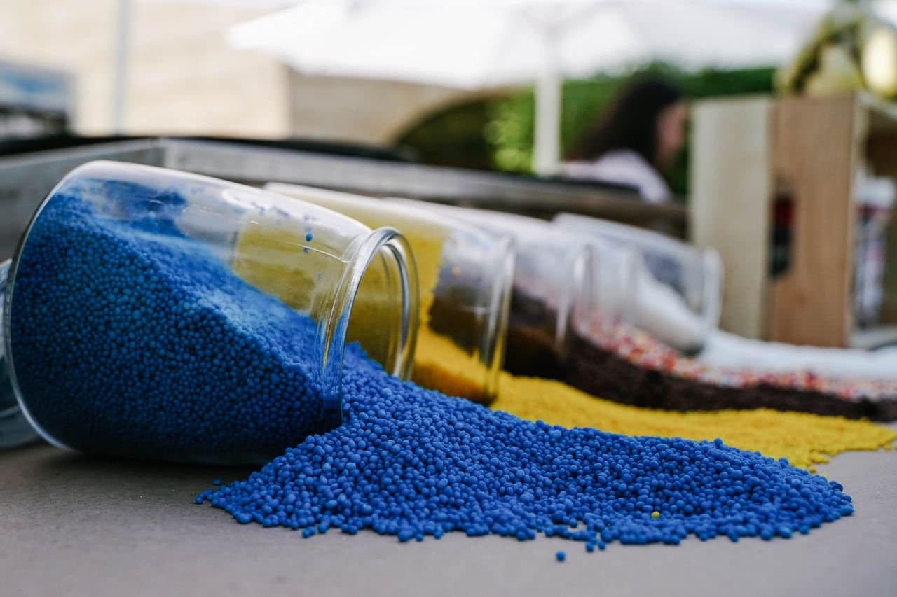 Colorful small beads spilled from jars, creating an eye-catching pattern outdoors.